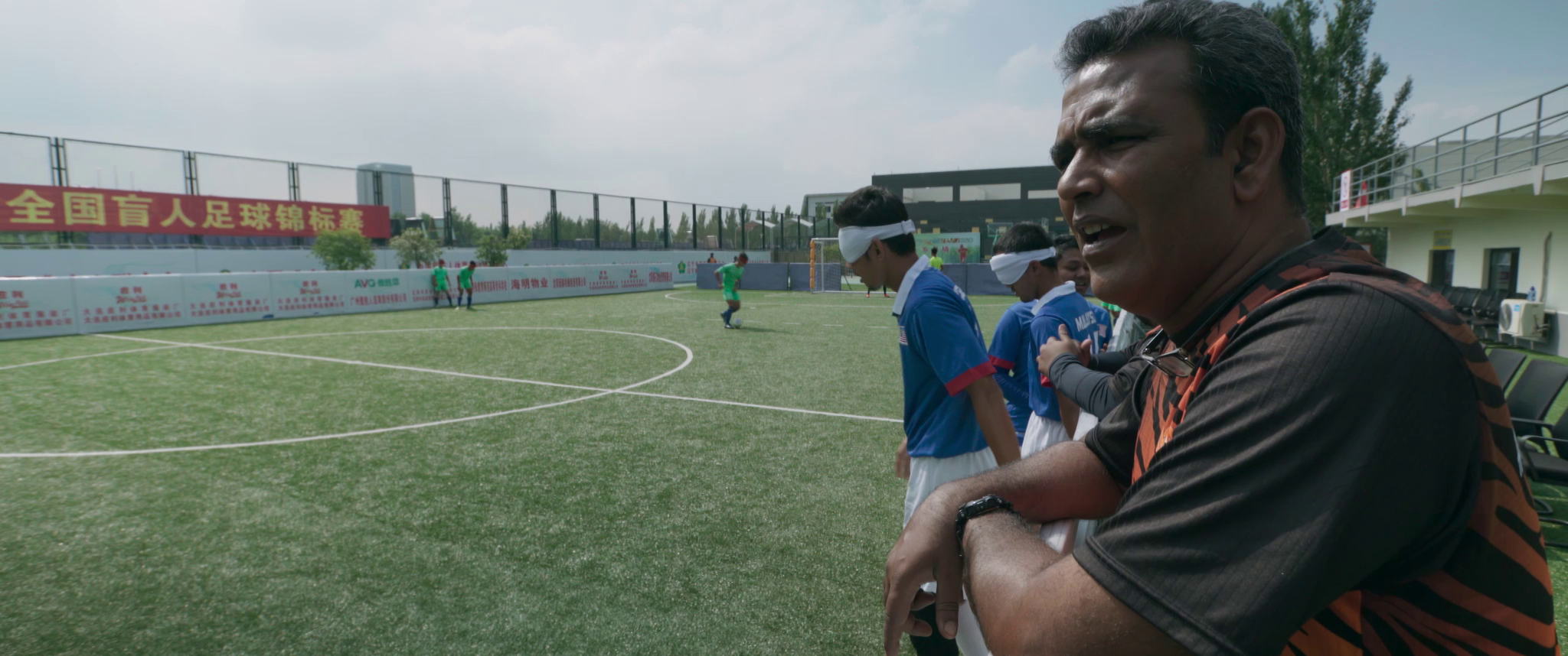 Coach Sunny is shouting instructions to his blind footballers from the sidelines.