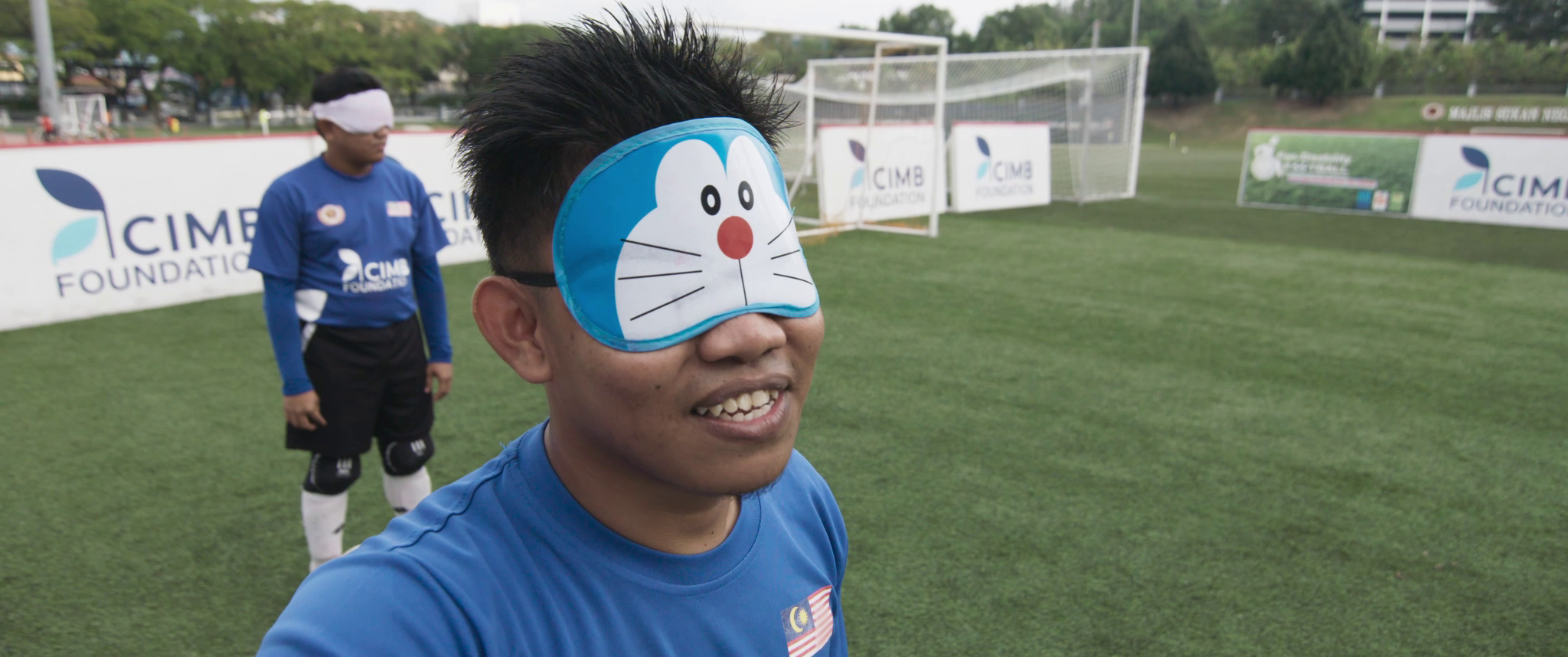 Pemain bola sepak Kenchot memakai penutup mata kartun Doraemon.