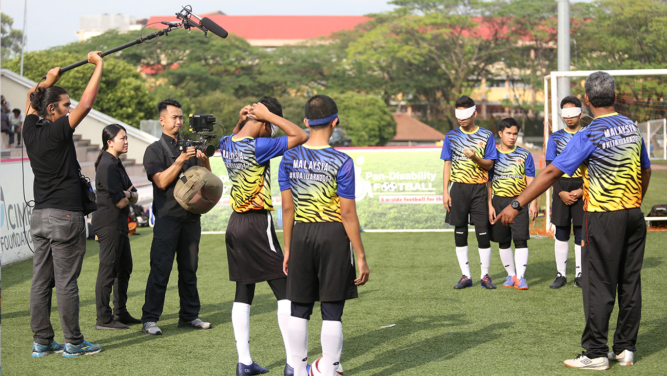 Krew kamera merakam jurulatih Sunny memberi arahan kepada pasukan bola sepaknya ketika sesi latihan di atas padang.